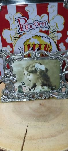 an old photo frame sitting on top of a piece of wood next to a popcorn box