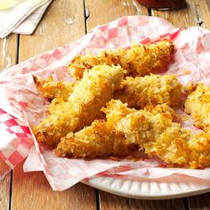 fried chicken sticks on a paper plate with red and white checkered napkins next to it