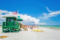 a lifeguard tower on the beach with people in the water and an american flag flying