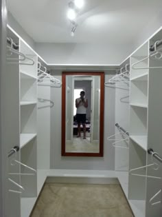 a man taking a selfie in front of a mirror and some white closets