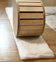 a roll of toilet paper sitting on top of a wooden table next to a white napkin