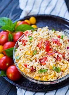 a bowl filled with rice and tomatoes next to some green leafy vegetables on a table