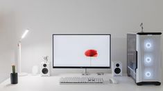 a desktop computer sitting on top of a white desk next to a monitor and speakers