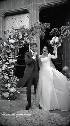 a man and woman standing in front of a doorway with flowers on the door way