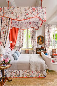 the bedroom is decorated in floral prints and orange curtains, along with an upholstered canopy bed