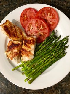 a white plate topped with asparagus, tomatoes and chicken