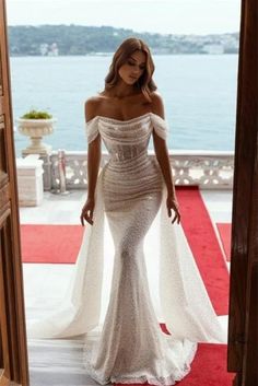 a woman in a white dress is standing on a red carpet and looking at the camera