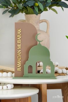 a green and beige baby's day card sitting on a table next to a potted plant