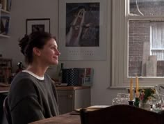 a woman sitting at a table in front of a window