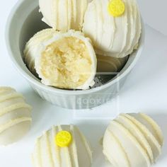 a bowl filled with white chocolate covered in frosting and lemons next to it