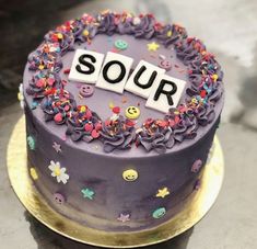 a purple cake with sprinkles and the word sour on top is sitting on a gold plate