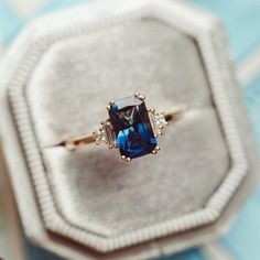 an engagement ring with a blue topaz surrounded by white and yellow diamonds in a velvet box