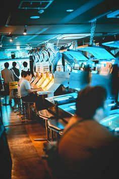 people sitting at tables in a restaurant with bright lights on the ceiling and blue lighting