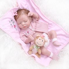 a baby doll laying on top of a pink blanket