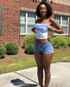 a woman standing on the sidewalk in denim shorts