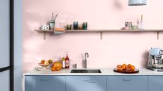 a kitchen with pink walls and blue cupboards on the counter top, along with various appliances