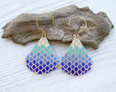 a pair of blue and white beaded earrings on top of a piece of wood