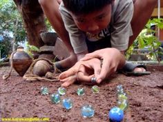 a young boy is playing with small glass pieces on the ground in front of him