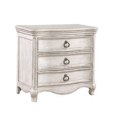 a white dresser with three drawers and two doors on the bottom drawer, in an antique style