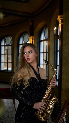 a woman in a black dress is holding a saxophone and looking at the camera with an intense look on her face