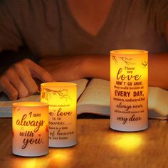 three lit candles sitting on top of a wooden table next to an open book with writing