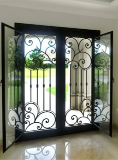 an iron door with glass panels and wrought designs on the sides, in front of a large window