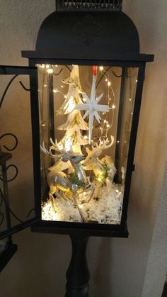 a lighted christmas tree in a glass box on top of a black stand with snowflakes