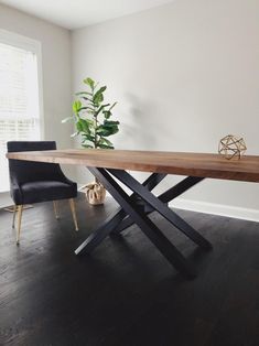 a wooden table with two black chairs and a potted plant