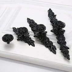 three black roses are sitting on top of a white surface, and one is in the middle