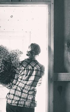 a woman standing in front of a window holding hay