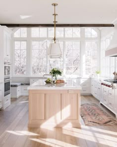 a large kitchen with white cabinets and an island in the middle, along with a rug on the floor