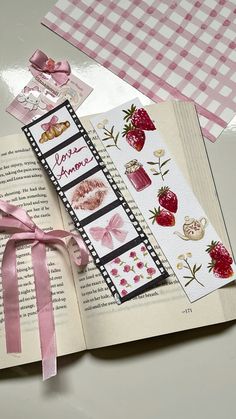 an open book with pink ribbon on top of it