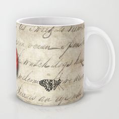 a coffee mug with writing on it and a red flower in the middle, sitting on a white surface