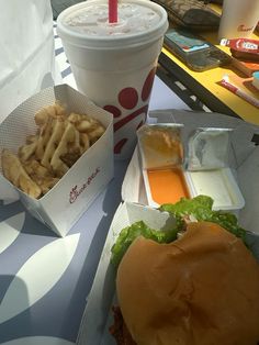 a hamburger and french fries are sitting on a table next to a cup of drink