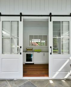 an open door leading to a kitchen with white cabinets and doors that lead into the outside