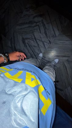 a person laying on top of a bed covered in a blue and yellow comforter