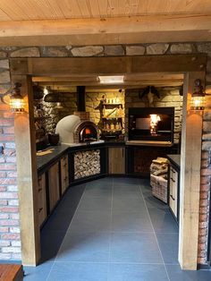 an outdoor kitchen with wood stoves and stone walls on either side of the door