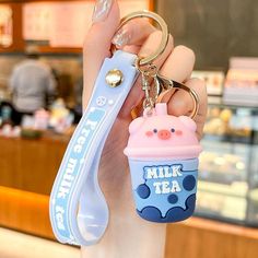 a person holding a keychain with a cup shaped like a milkshake