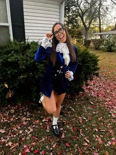 a woman posing in front of a house with her hands on her hips and wearing glasses