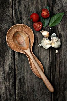 a wooden spoon and some garlic on a table with tomatoes, peppers, and basil