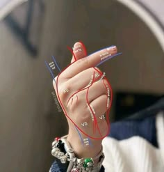 a woman's hand with red and blue nails pointing to the heart on her finger