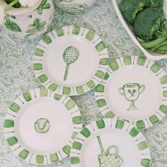 four green and white plates with tennis designs on them sitting next to broccoli