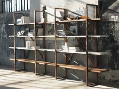 a wooden shelf with books on it in front of a concrete wall and metal bars