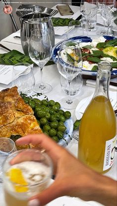 a person holding a wine glass in front of a table full of food and drinks