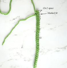 a green crochet hook is shown on a white surface with measurements for each hook