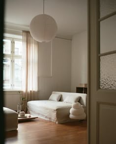 a living room filled with furniture and a large white lamp hanging from the ceiling next to a window