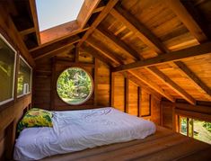 there is a bed in the loft with a round window on it's side