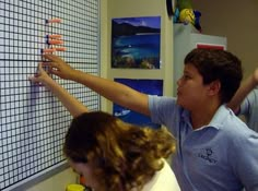 two boys and a girl are looking at a wall calendar