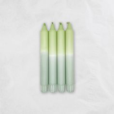 four green and white candles sitting on top of each other