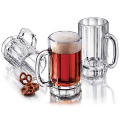 two mugs with beer and pretzels next to each other on a white surface